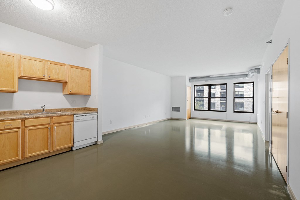 an empty kitchen and living room with white walls and wood cabinets