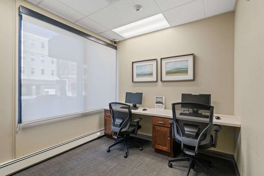 an office with two desks and two chairs and a window