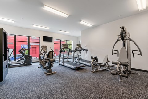 a gym with weights and cardio equipment in a building with windows