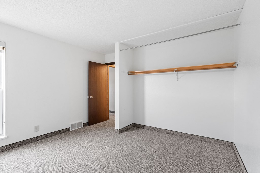 an empty room with a white wall and a door to a closet