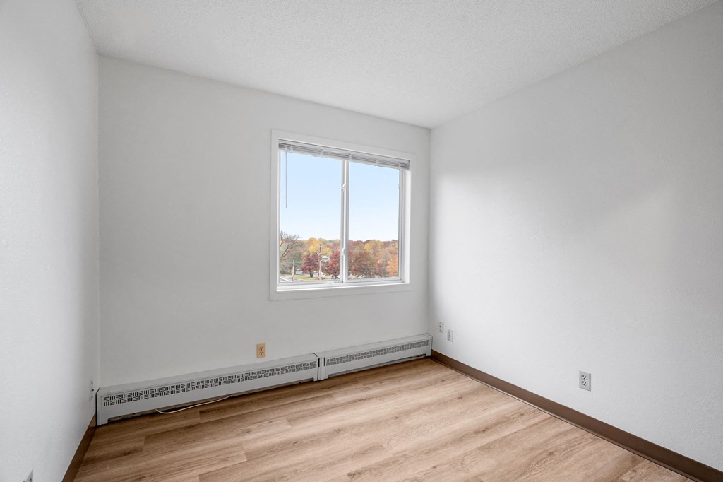 the living room of an empty apartment with wood flooring and a window