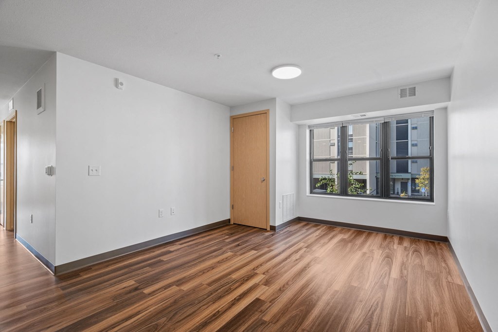 an empty living room with wood floors and a window