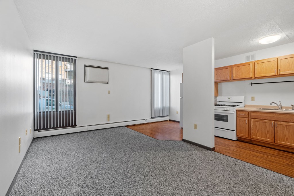 an empty living room and kitchen with wood cabinets and a window