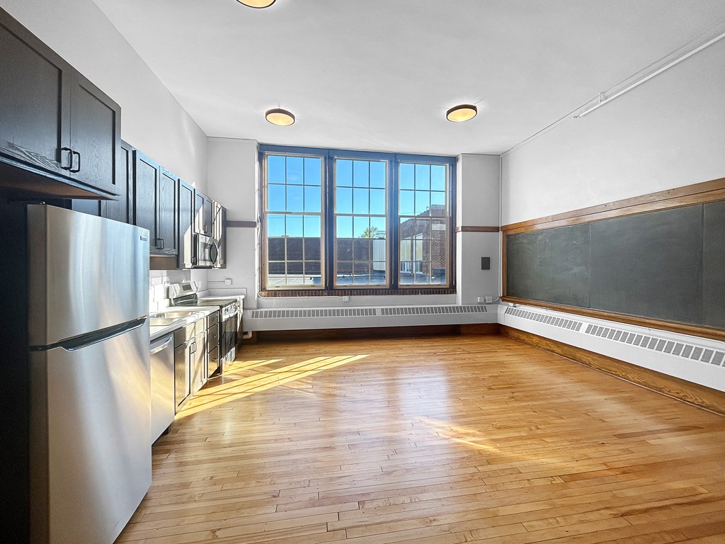 an empty kitchen with wood floors and a window