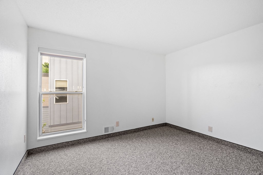 an empty room with a window and a carpet