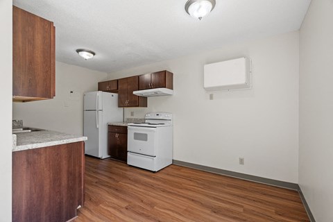 a kitchen with white appliances and wooden flooring and a white refrigerator