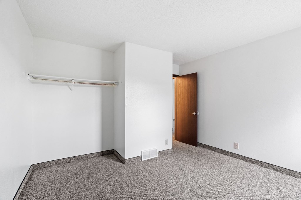 an empty room with a white wall and a door to a closet