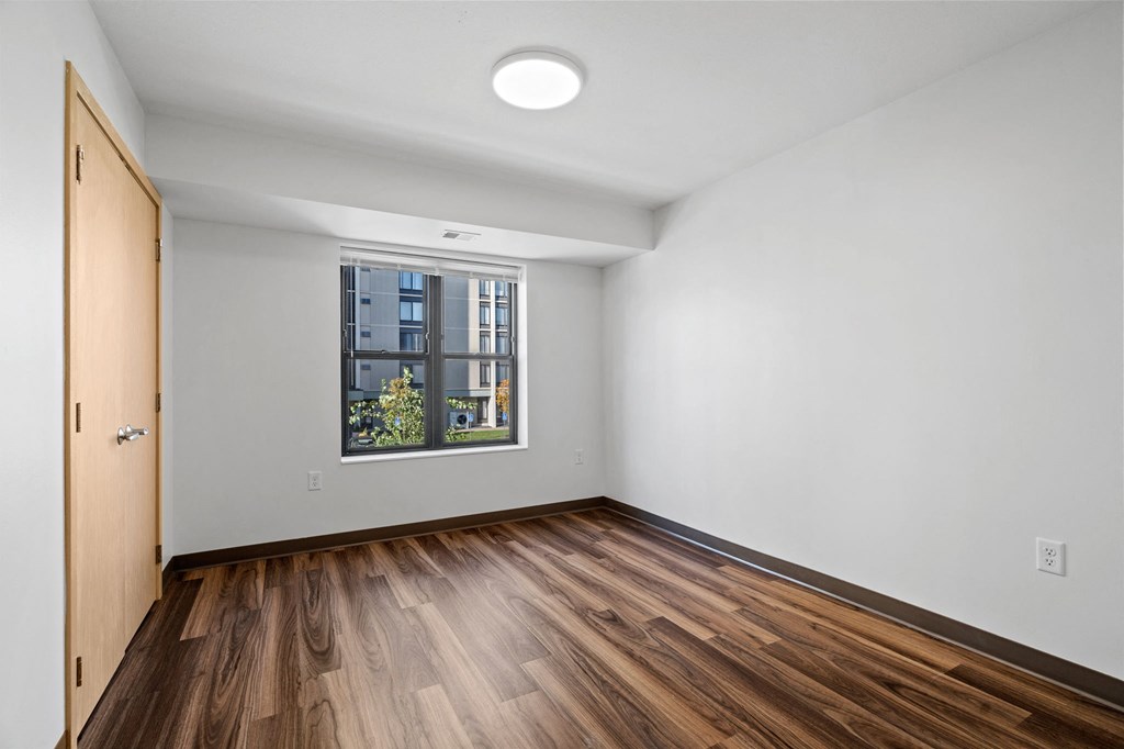 an empty living room with wood flooring and a window