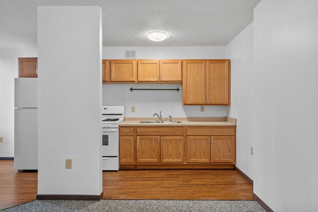 an empty kitchen with wooden cabinets and white appliances