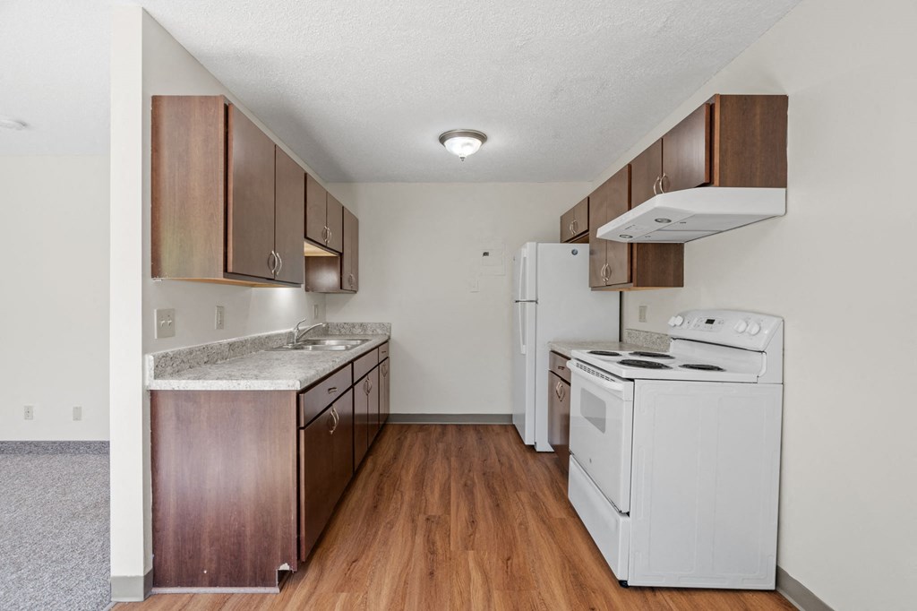 an empty kitchen with white appliances and wood floors