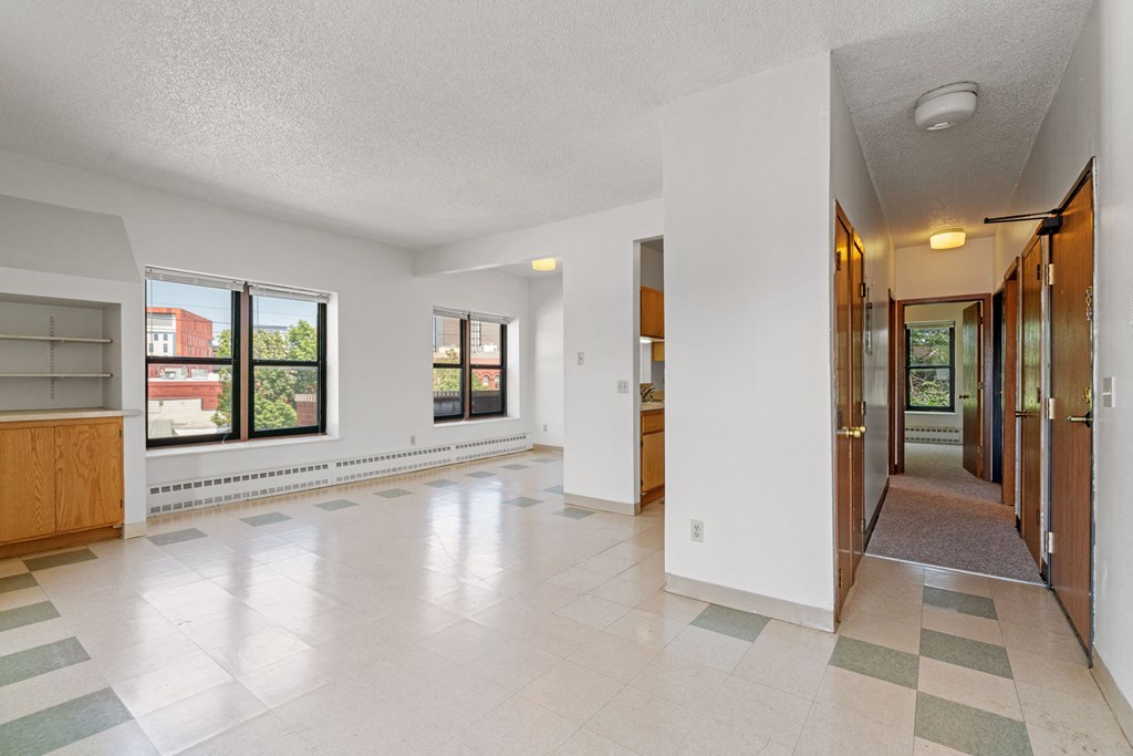 the living room and entryway of an empty house with large windows