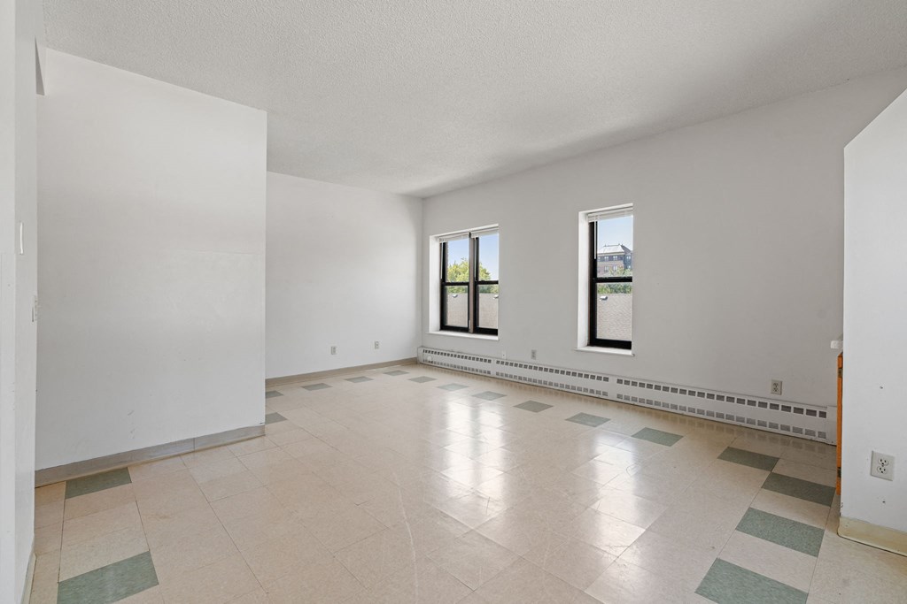 a spacious living room with white walls and tile floors