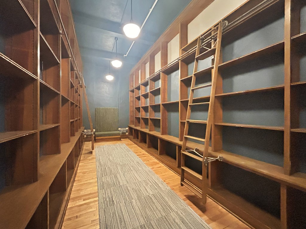 a library with wooden shelves and a rug
