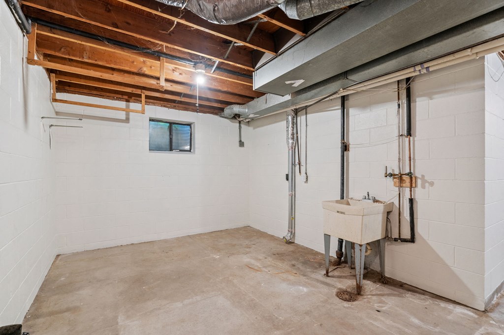 the basement of a house with a sink in the corner