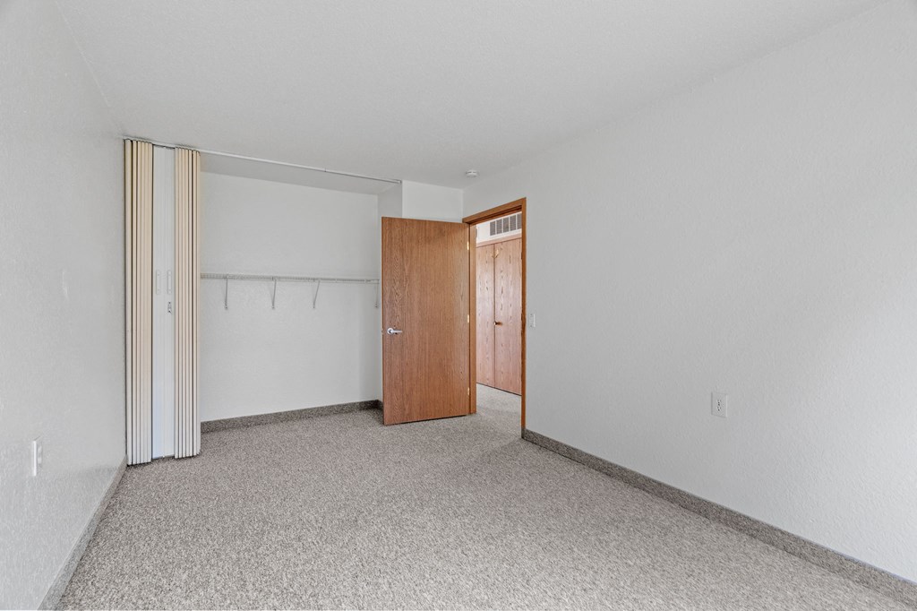 a bedroom with a door to a closet and a carpeted floor