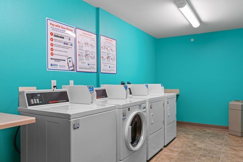 a laundry room with washers and dryers and a row of washing machines