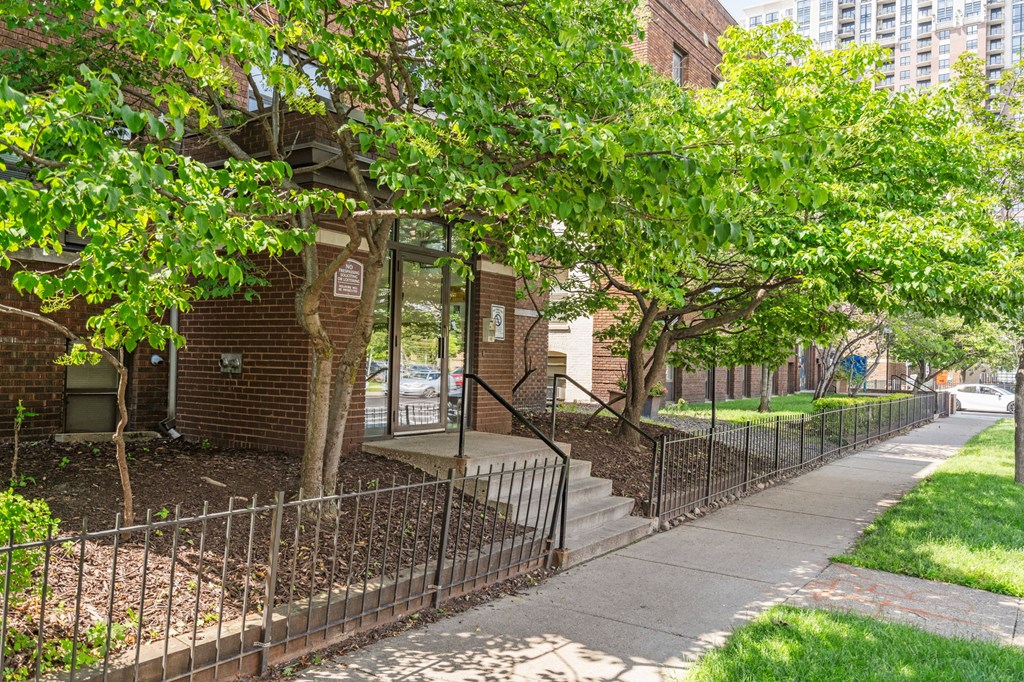 a sidewalk in front of a brick building with trees