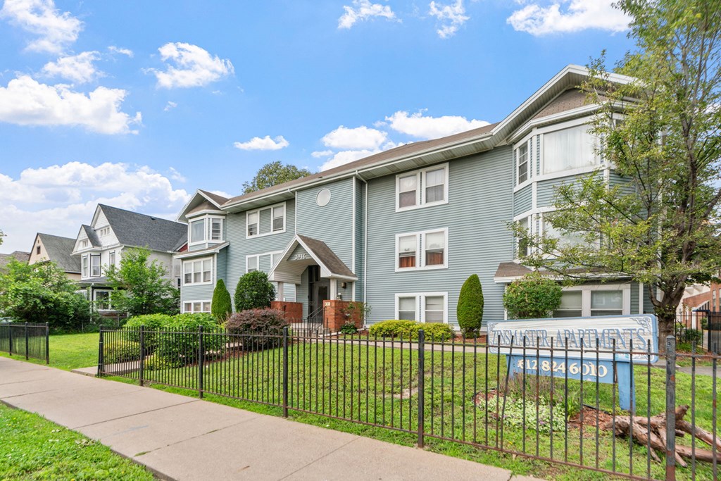 a blue house with a yard and a fence in front of it