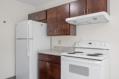 a kitchen with white appliances and wooden cabinets and a refrigerator