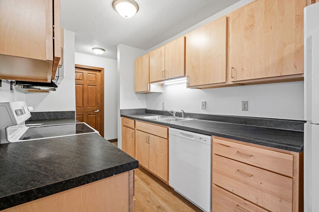 a kitchen with wood cabinets and black counter tops and white appliances