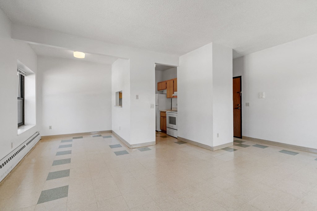 the living room and kitchen of an empty apartment with white walls and tile flooring