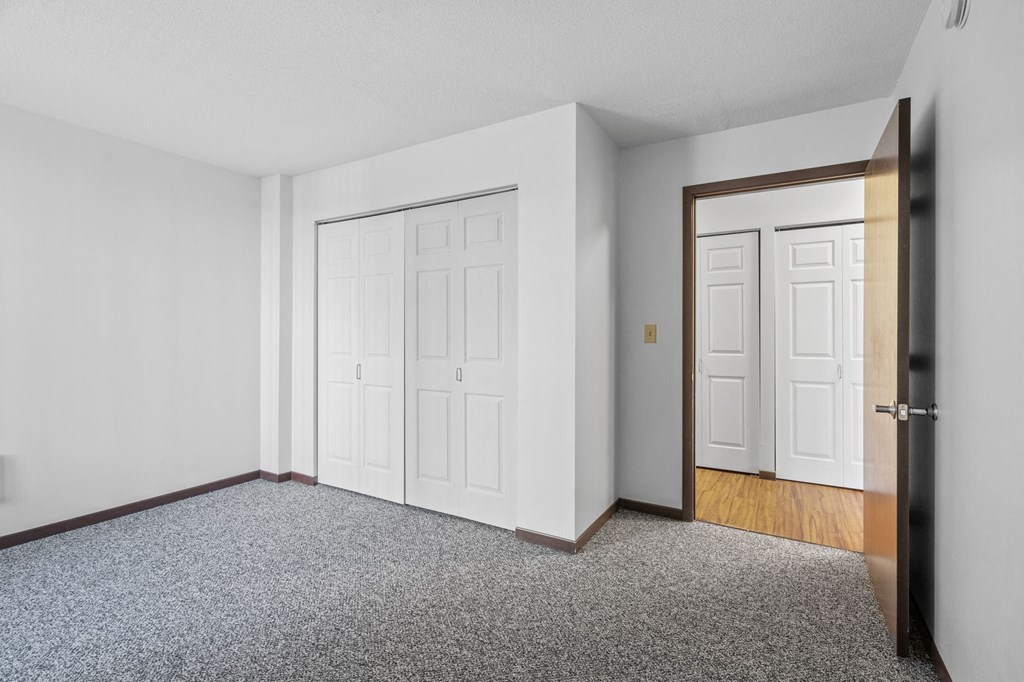 an empty room with white walls and a door to a bedroom