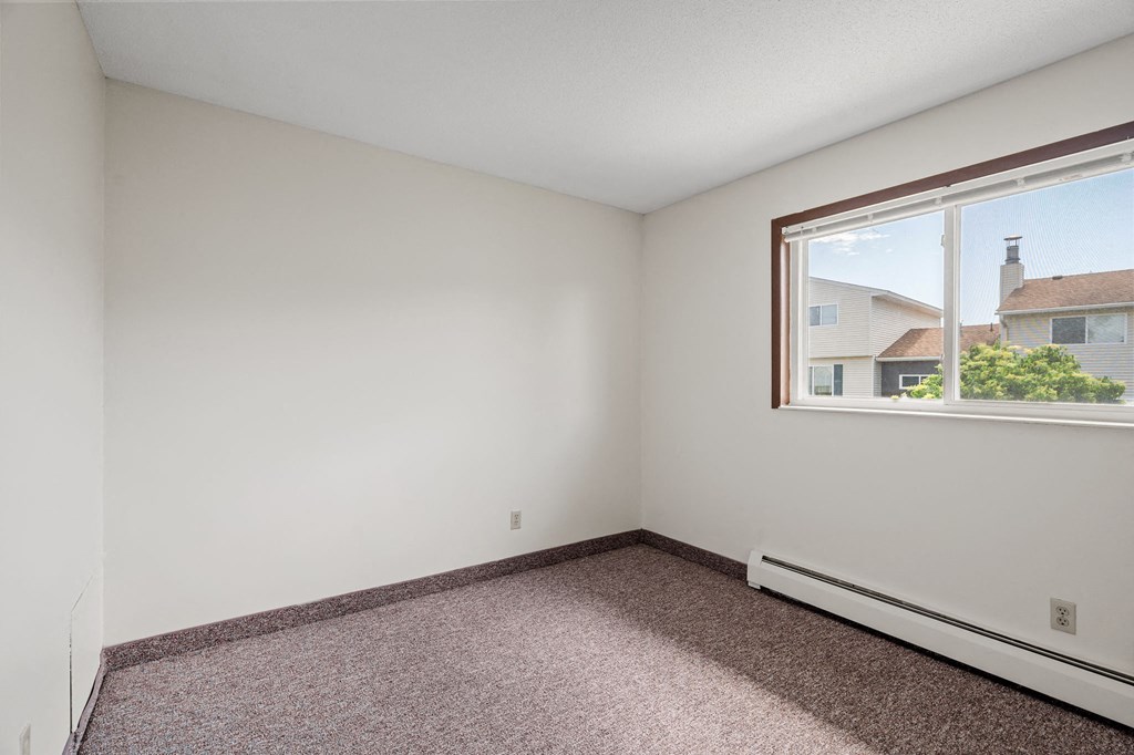 a bedroom with a large window and a carpeted floor