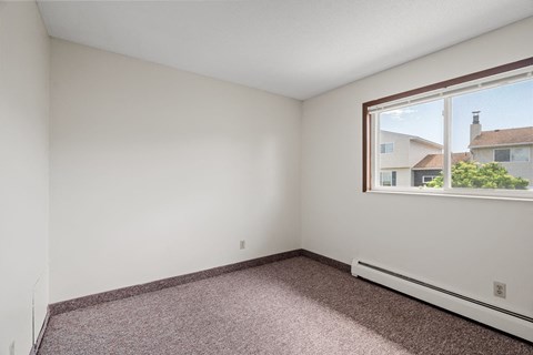 a bedroom with a large window and a carpeted floor