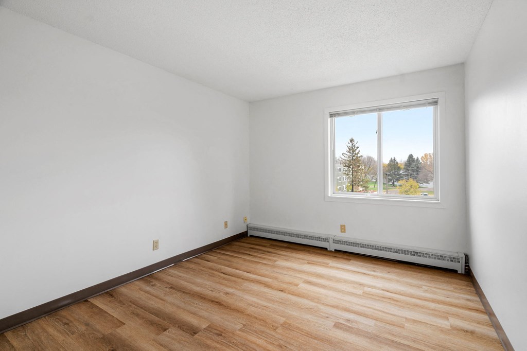 the living room of an empty house with wood floors and a window