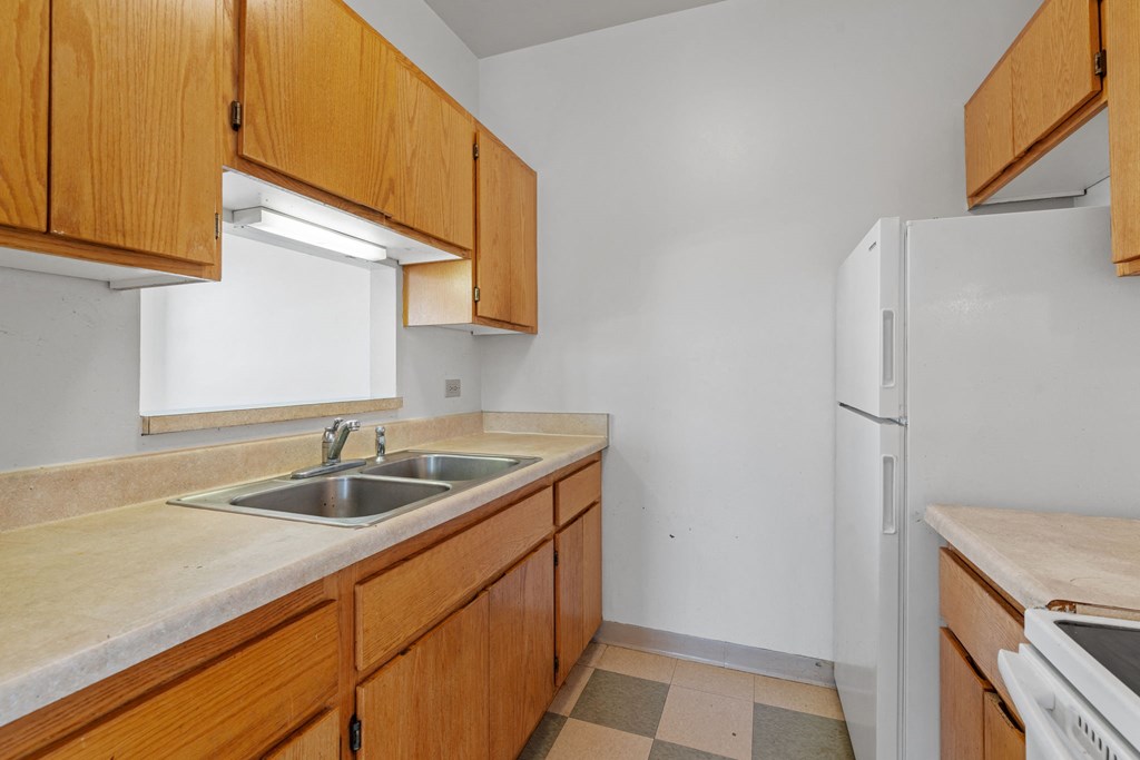 a kitchen with wooden cabinets and a sink and a refrigerator