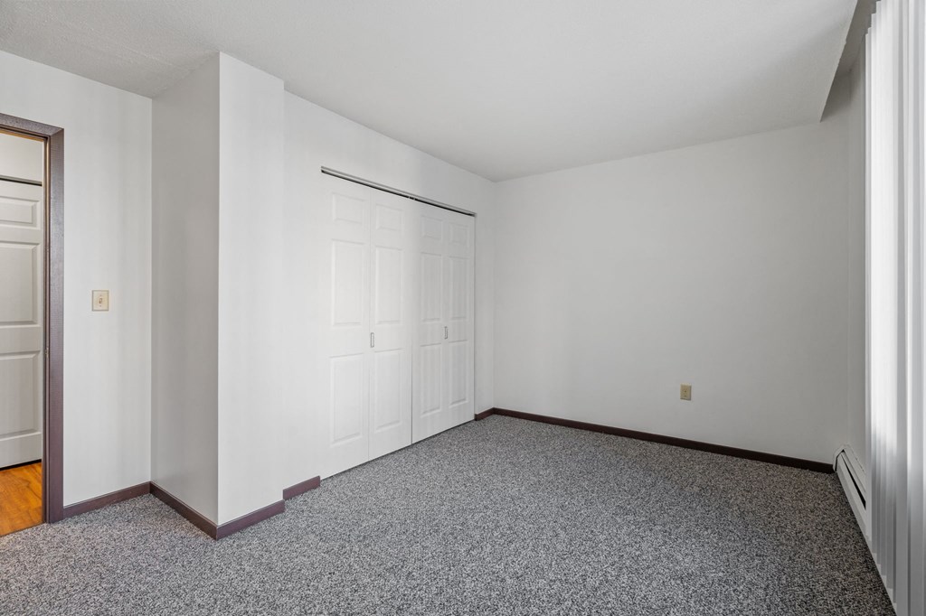 a bedroom with white walls and carpet and a white door