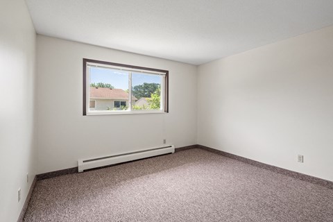 an empty room with a window and carpet