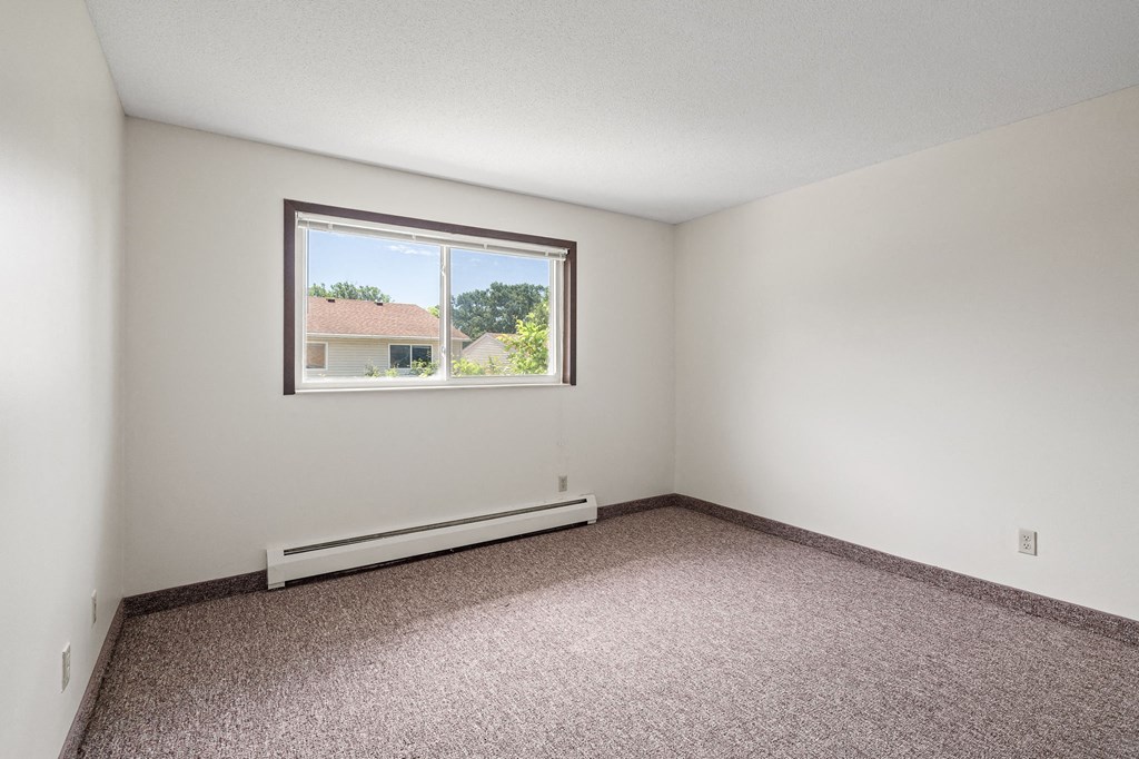 an empty room with a window and carpet