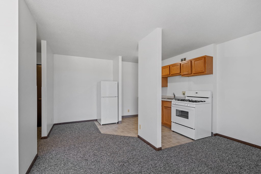 an empty kitchen with white appliances and wooden cabinets