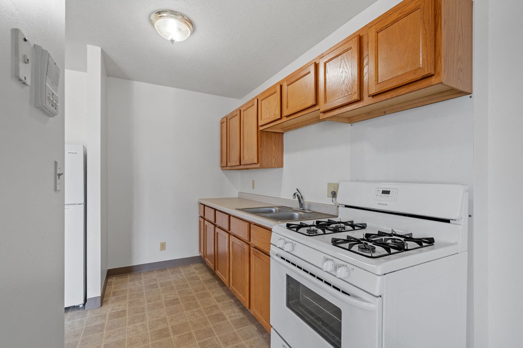 an empty kitchen with white appliances and wooden cabinets