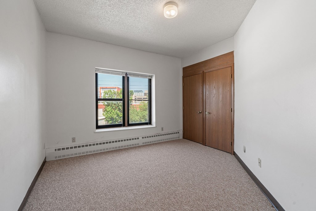 an empty bedroom with a window and a closet