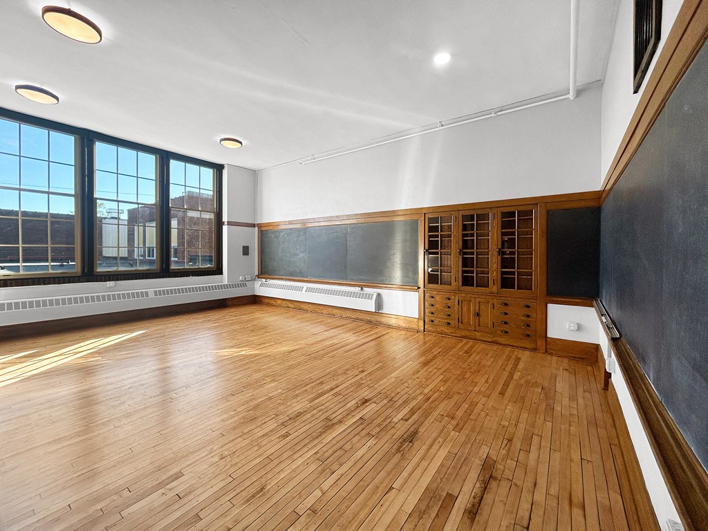 an empty room with wood floors and a chalkboard on the wall