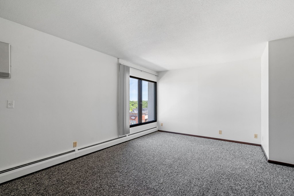 the living room of a house with white walls and a window