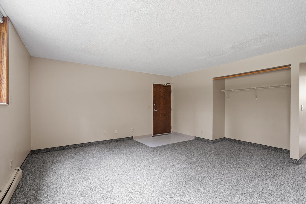an empty living room with a door to a closet