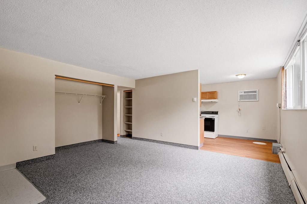an empty living room with a door to a closet and a window