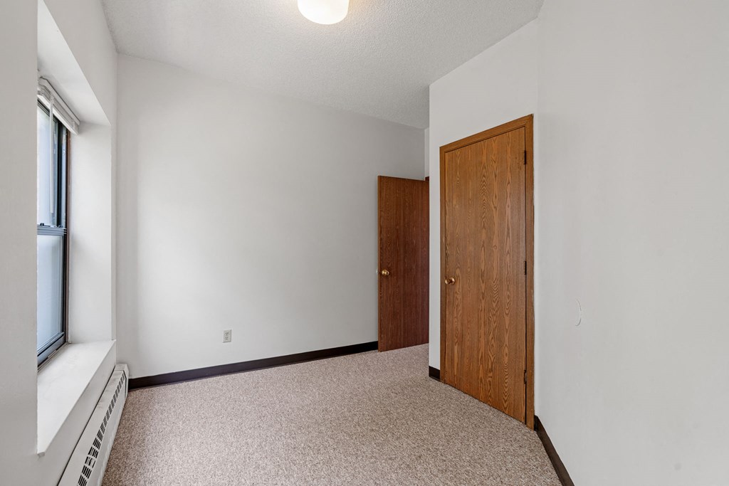 a bedroom with white walls and a wooden door and a window