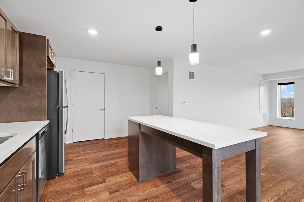 a kitchen with a white counter top and a stainless steel refrigerator