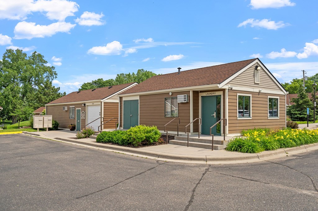 a brown house with green doors and a parking lot