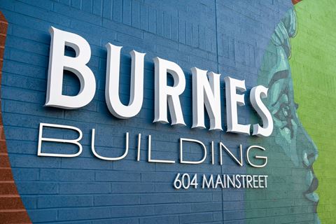 a sign for burns building on a blue brick wall