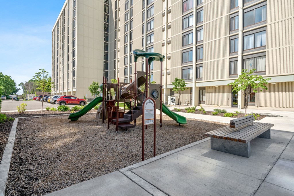 a playground in front of an apartment building with a swing set