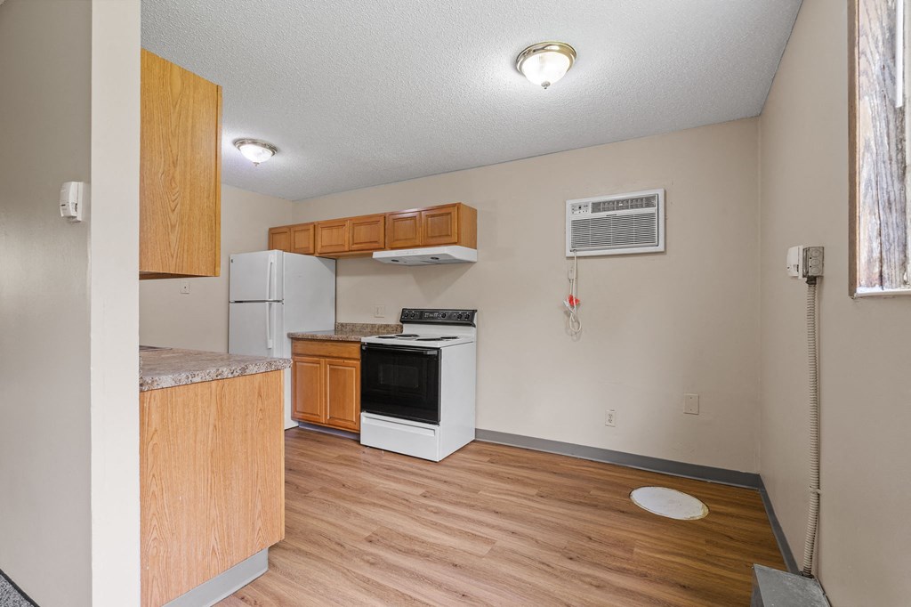 an empty kitchen with wood flooring and a stove and refrigerator