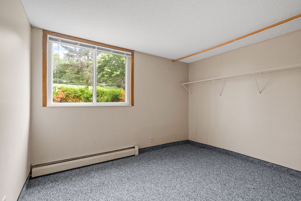 an empty room with a window and clothes racks