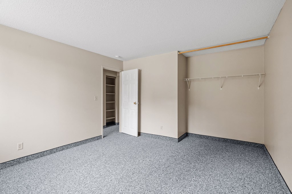an empty room with a closet and a door to a hallway