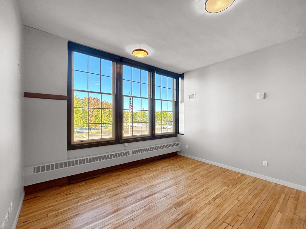 an empty living room with wood floors and large windows