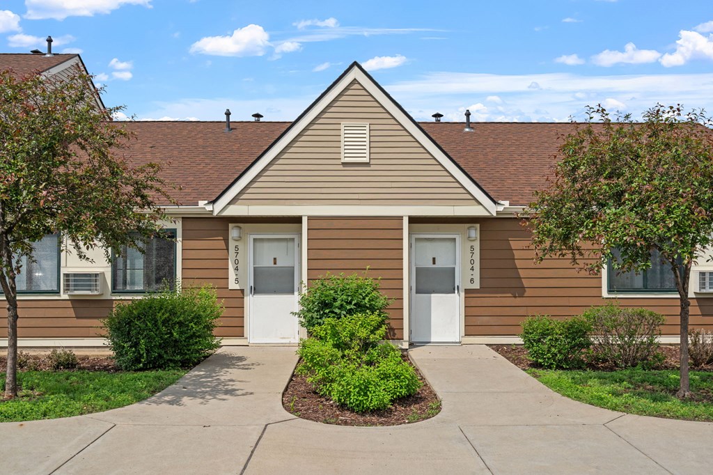a brown house with a sidewalk in front of it